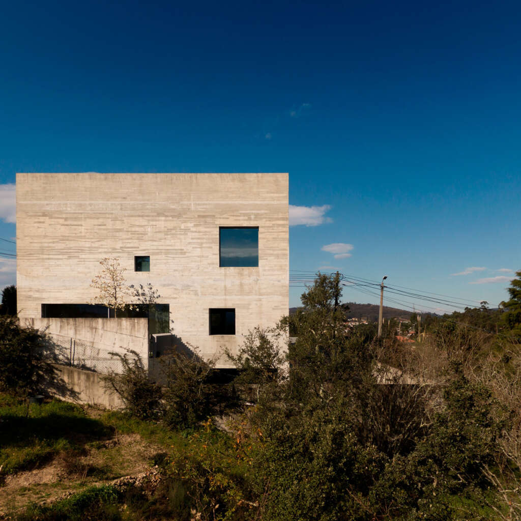 This concrete house in Portugal uses openings to frame pieces of the distant landscape