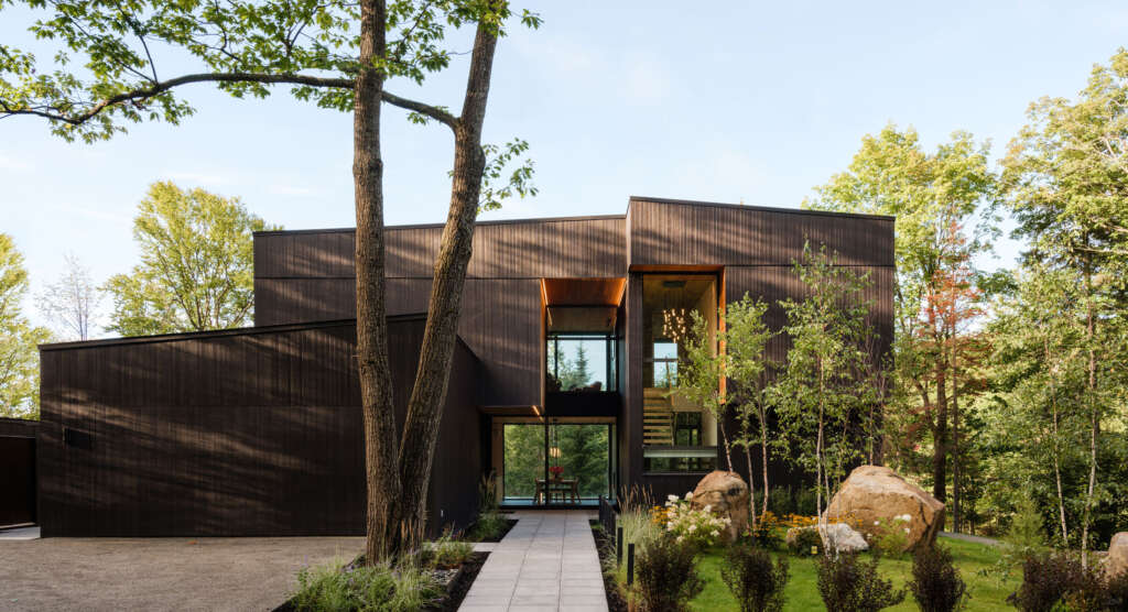 MU Architecture design getaway home in Quebec featuring an entrance chiseled between rock-like volumes