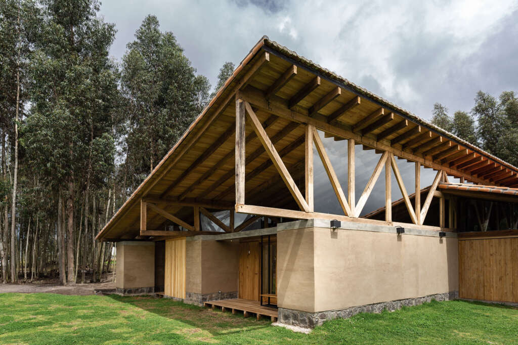 Rammed earth house in Ecuador features massive wooden trusses